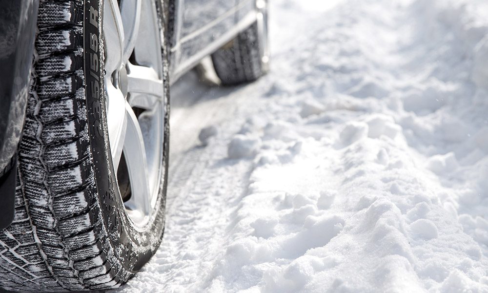 Blog - Close Up of Car Tires on the Passenger's Side of a Car That is Sitting in the Snow with Tire Tracks